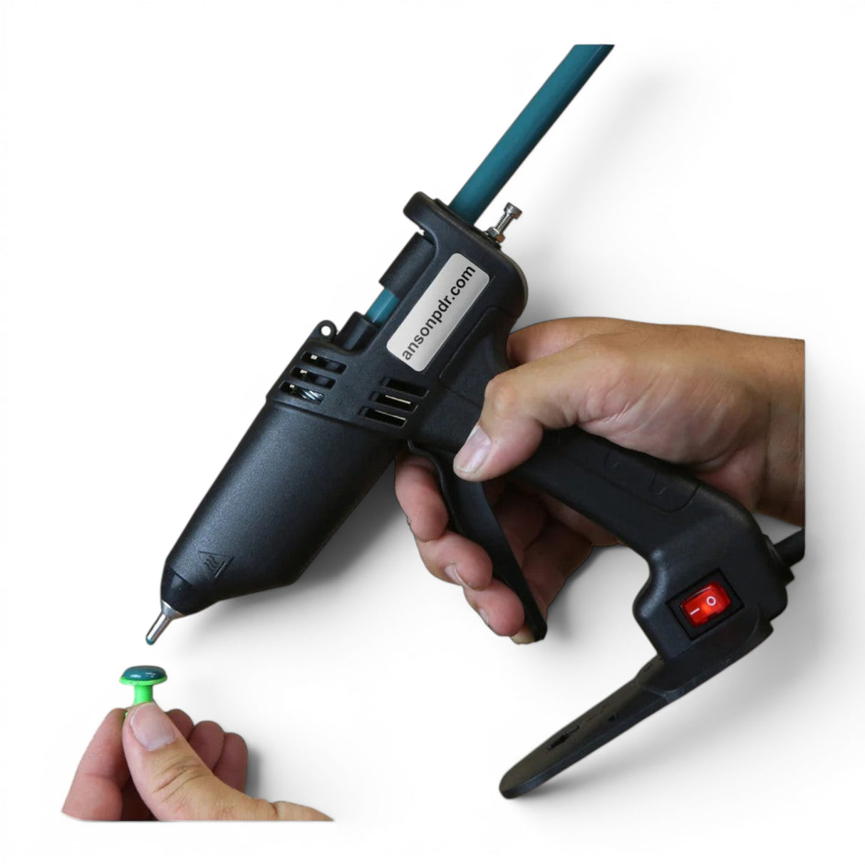 Anson PDR glue gun with a teal rod, held by a hand, preparing to attach a green tab.