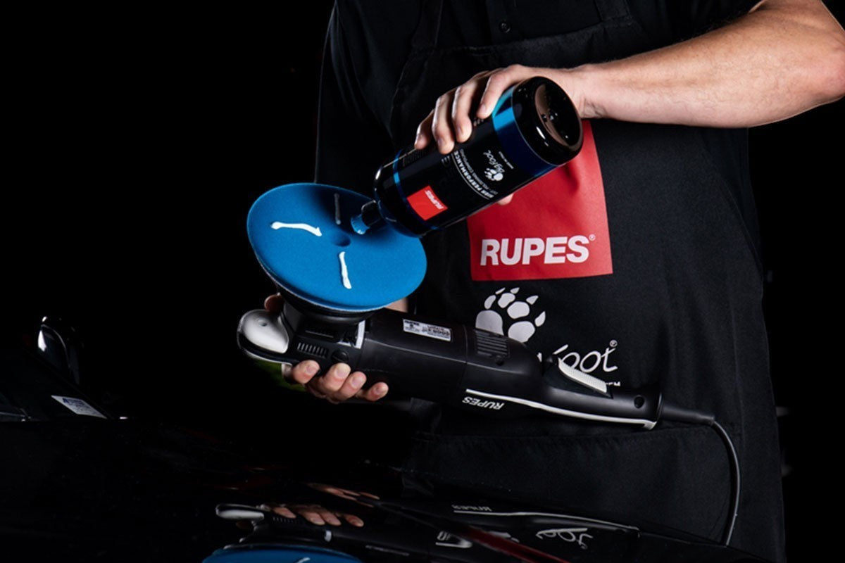 Anson PDR technician applying RUPES D-A COARSE polishing compound to a blue foam pad on a BigFoot dual action polisher.