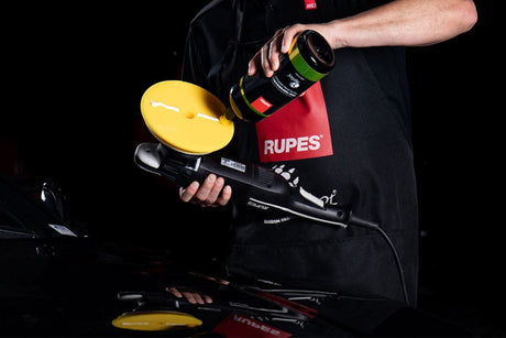 Anson PDR technician applying polishing compound to a yellow Rupes D-A FINE finishing foam pad on a polisher.