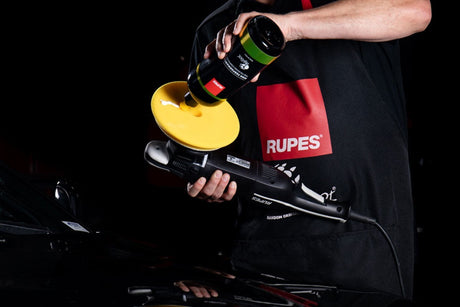 Anson PDR technician applying Rupes D-A FINE polishing compound to a yellow foam pad on a dual action polisher.