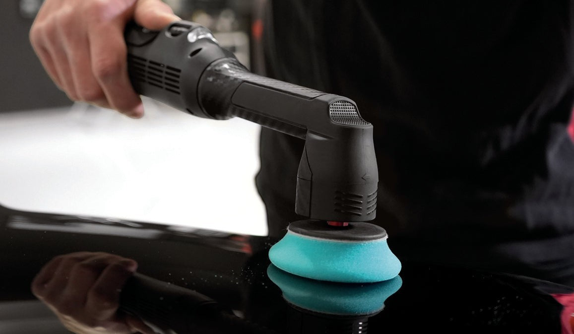 Anson PDR Rupes BigFoot iBrid Nano II polisher with a blue foam pad being used on a black car surface for detailing.