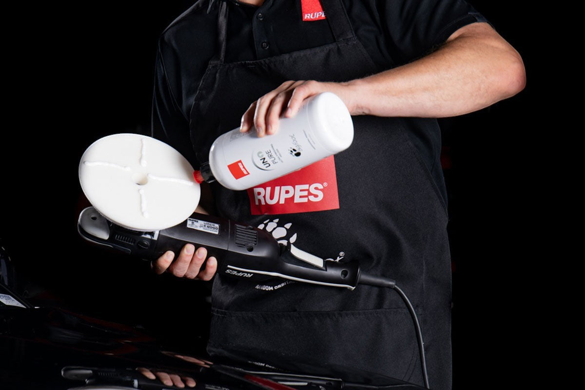 Anson PDR technician applying UNO PURE polish to a white Rupes D-A ULTRA-FINE foam pad on a dual action polisher.