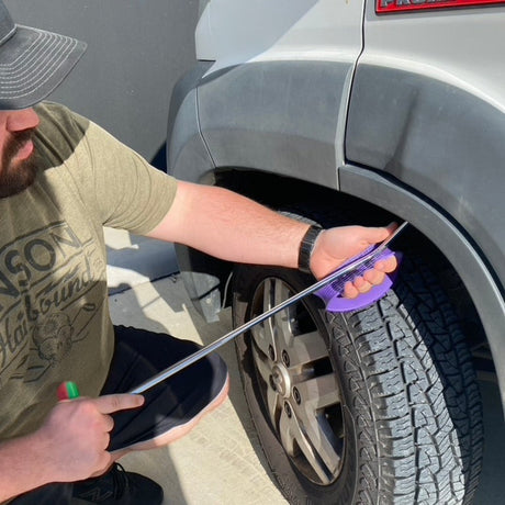 Anson PDR Stuckey Hand Shield, a purple tool used to protect hands during auto body repair near a tire.