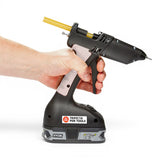 Anson PDR Trifecta dual temperature glue gun held by a hand, with a yellow glue stick inserted. Features a Ryobi 18V battery.